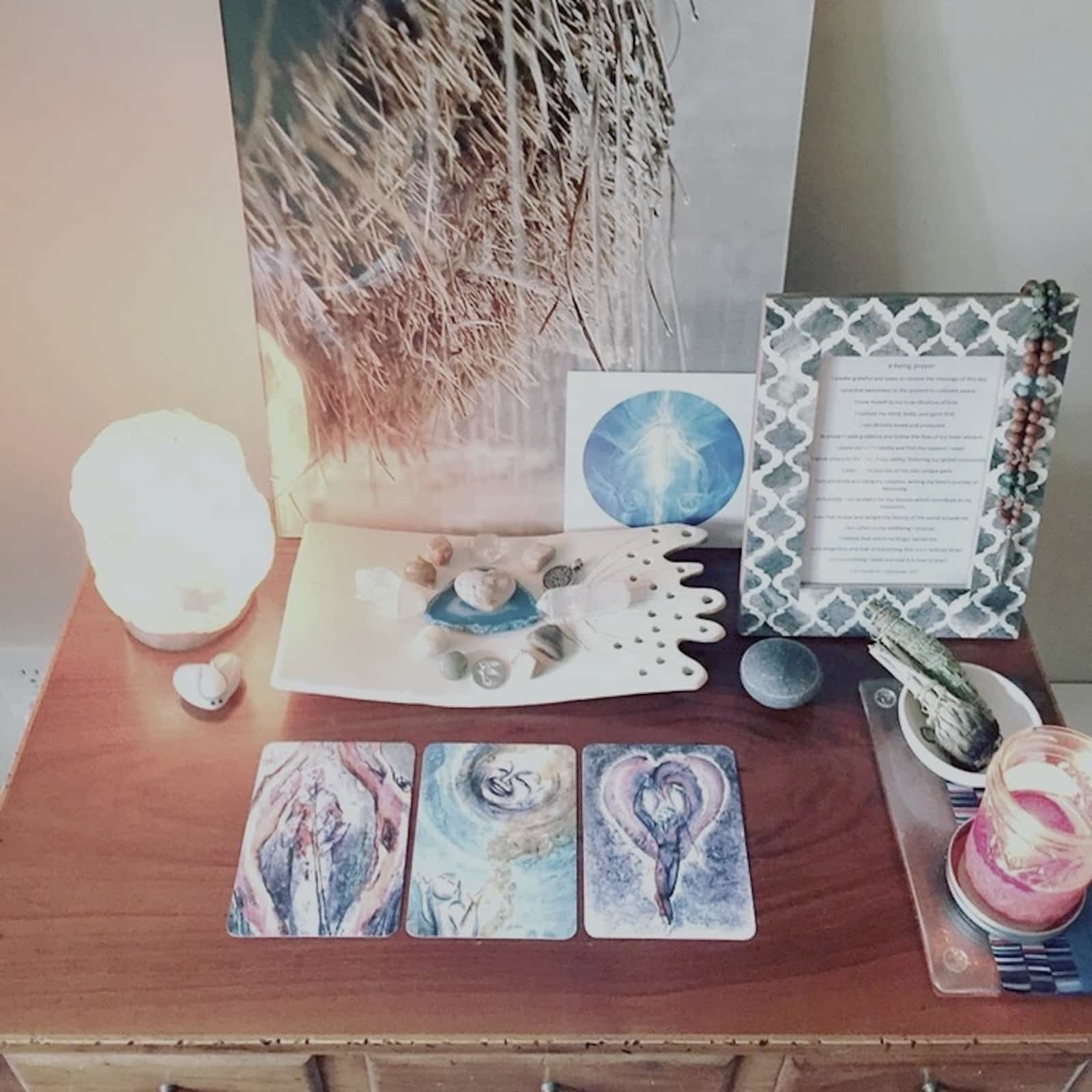 Erin Vivian's DIY home alter displaying a salt lamp, tarot cards, a tray of crystals, and other images and objects that are meaningful to her.