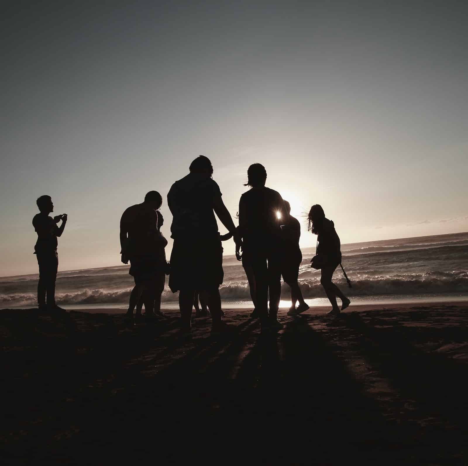 A family is shown as silhouettes at the beach by the ocean.