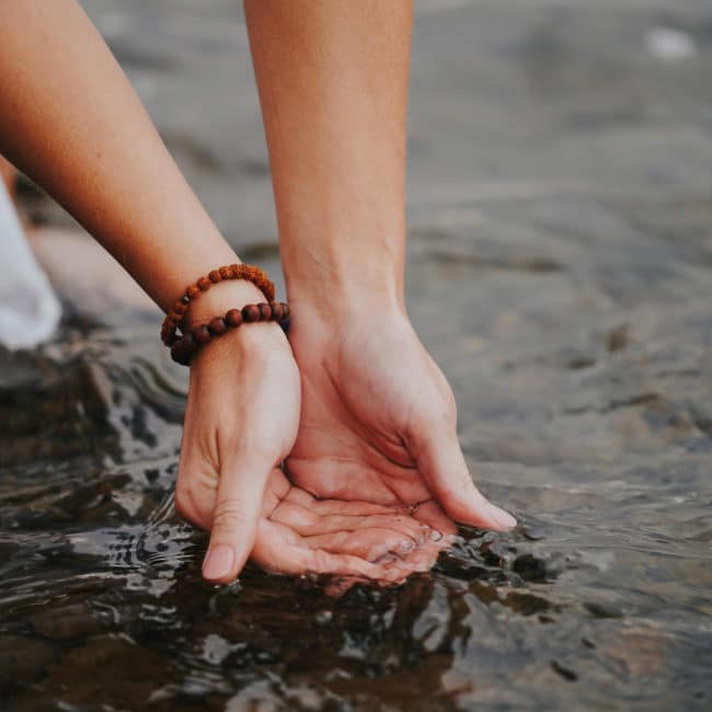 Erin Vivian's hands in the river, cupping the water as it runs out of her hands. The water symbolizes our ability to 'get in the flow' of life with Energy Healing.