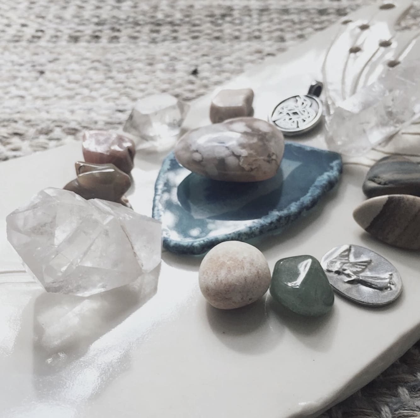 A crystal grid of many differently colored stones on a tray displayed on Erin Vivian's DIY home altar.
