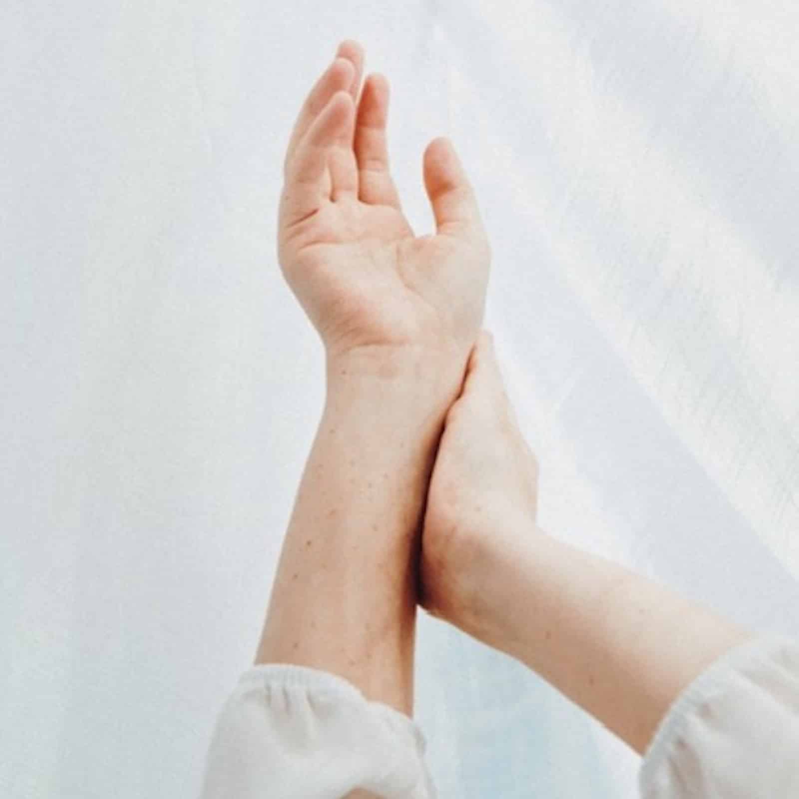 An image of a person's hands intertwined in front of a white backdrop. Muscle testing is also known as applied kinesiology.